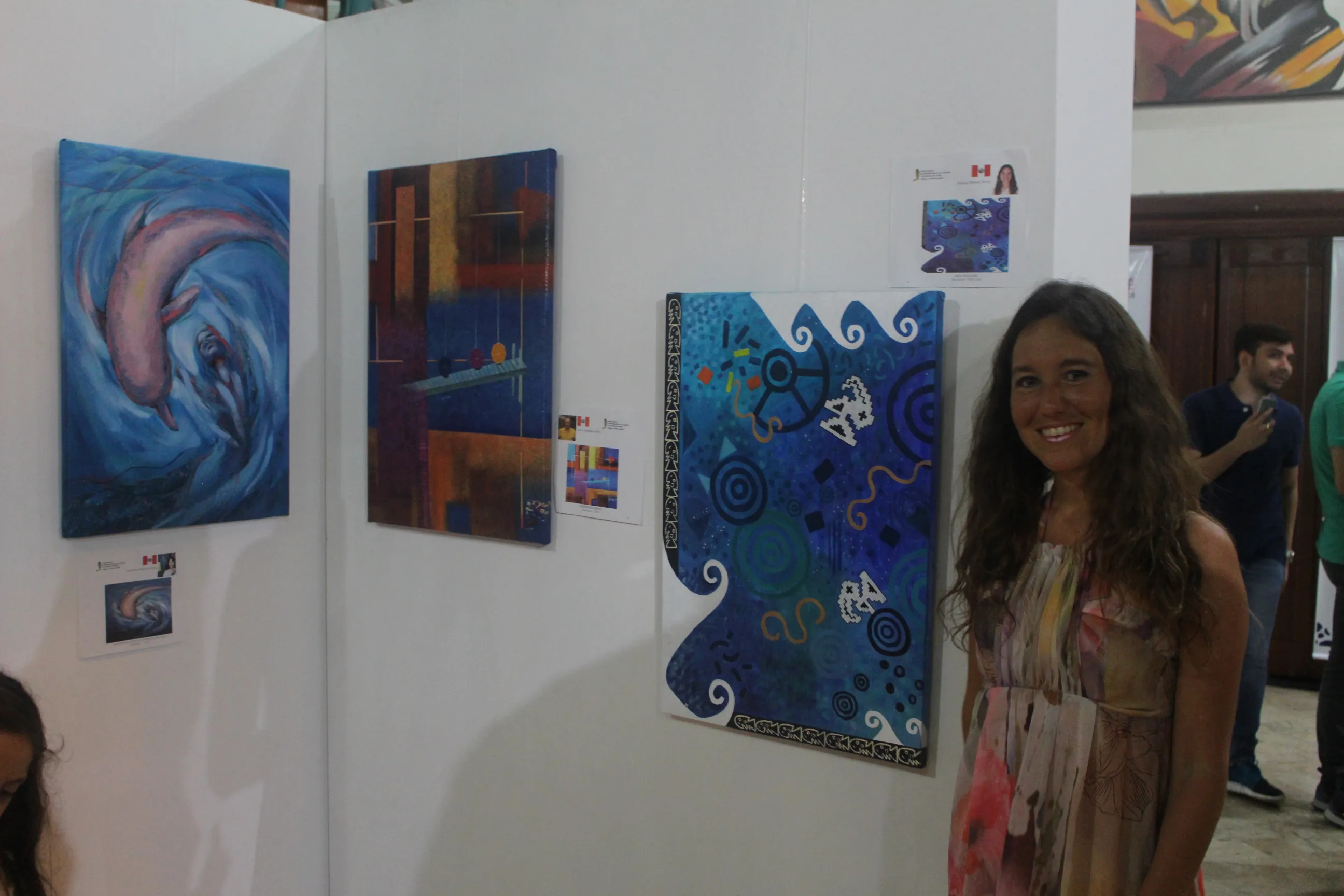 Ximena Heraud beside her blue marine-themed abstract paintings hung at the group exhibition in Sincelejo, Colombia