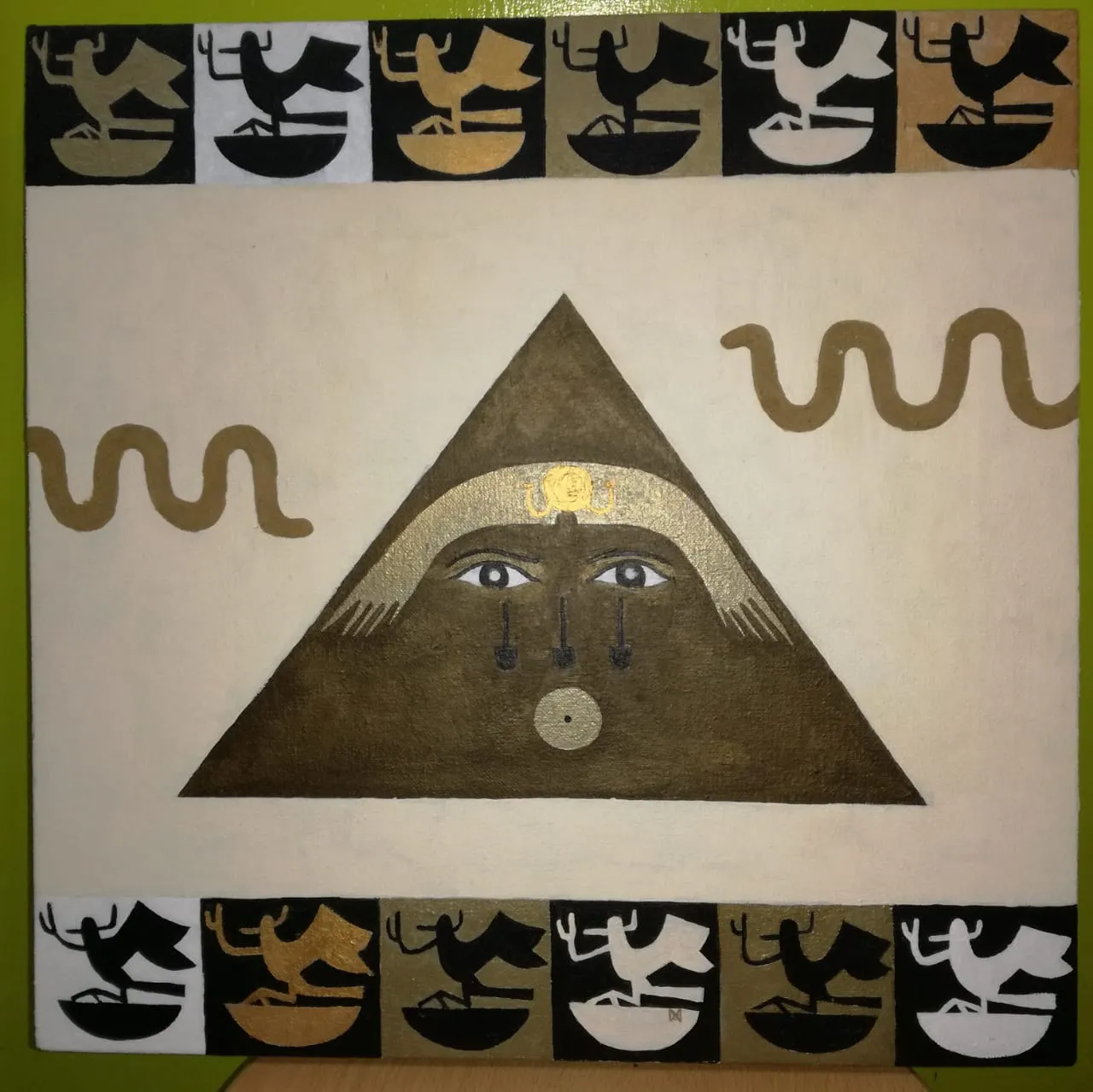 Painting of a brown pyramid enclosing a stylized face with gold headdress on a cream ground, flanked by gold serpent scrolls and bordered top and bottom by rows of black, white and gold figures in boats.